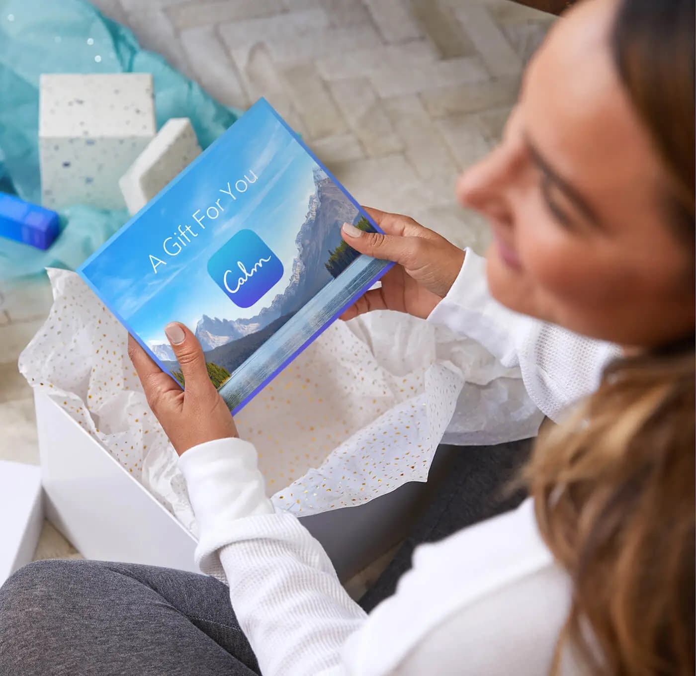 Woman holding a gift certificate for a year of Calm Premium and smiling